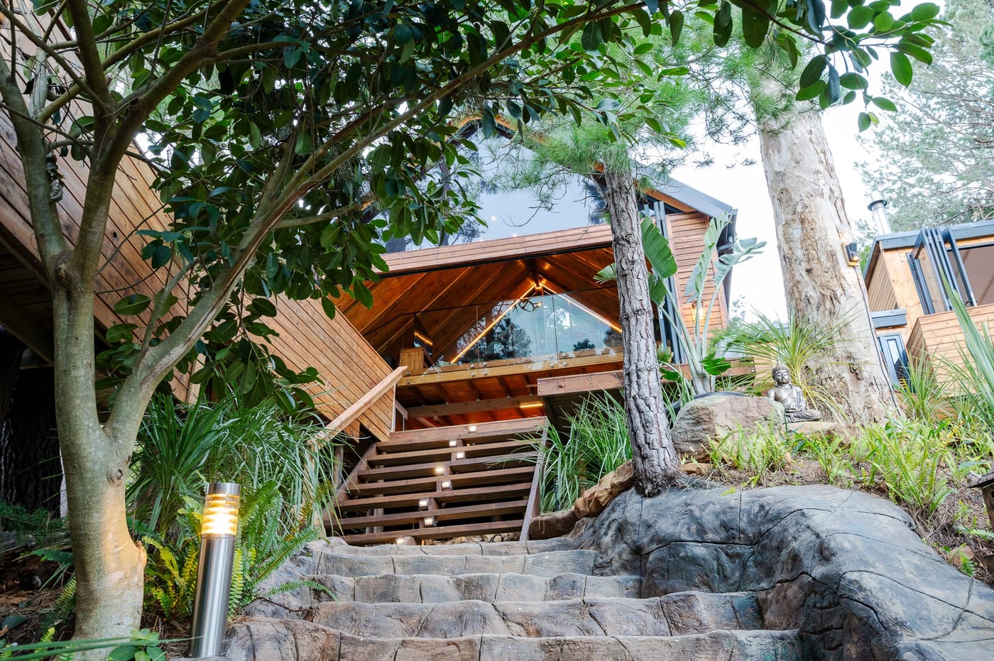 The lit stairs up to the A-frame, a Buddha seated on the rockery alongside