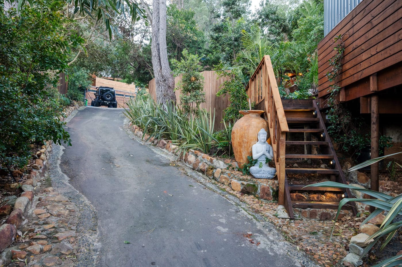A seated Buddha and clay urn beside the timber steps up to the cabin deck