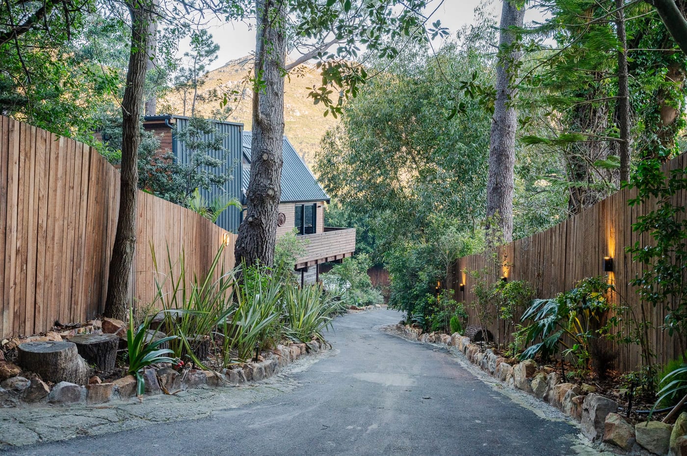 The private drive at dusk, lit timber fencing leading up to the cabins
