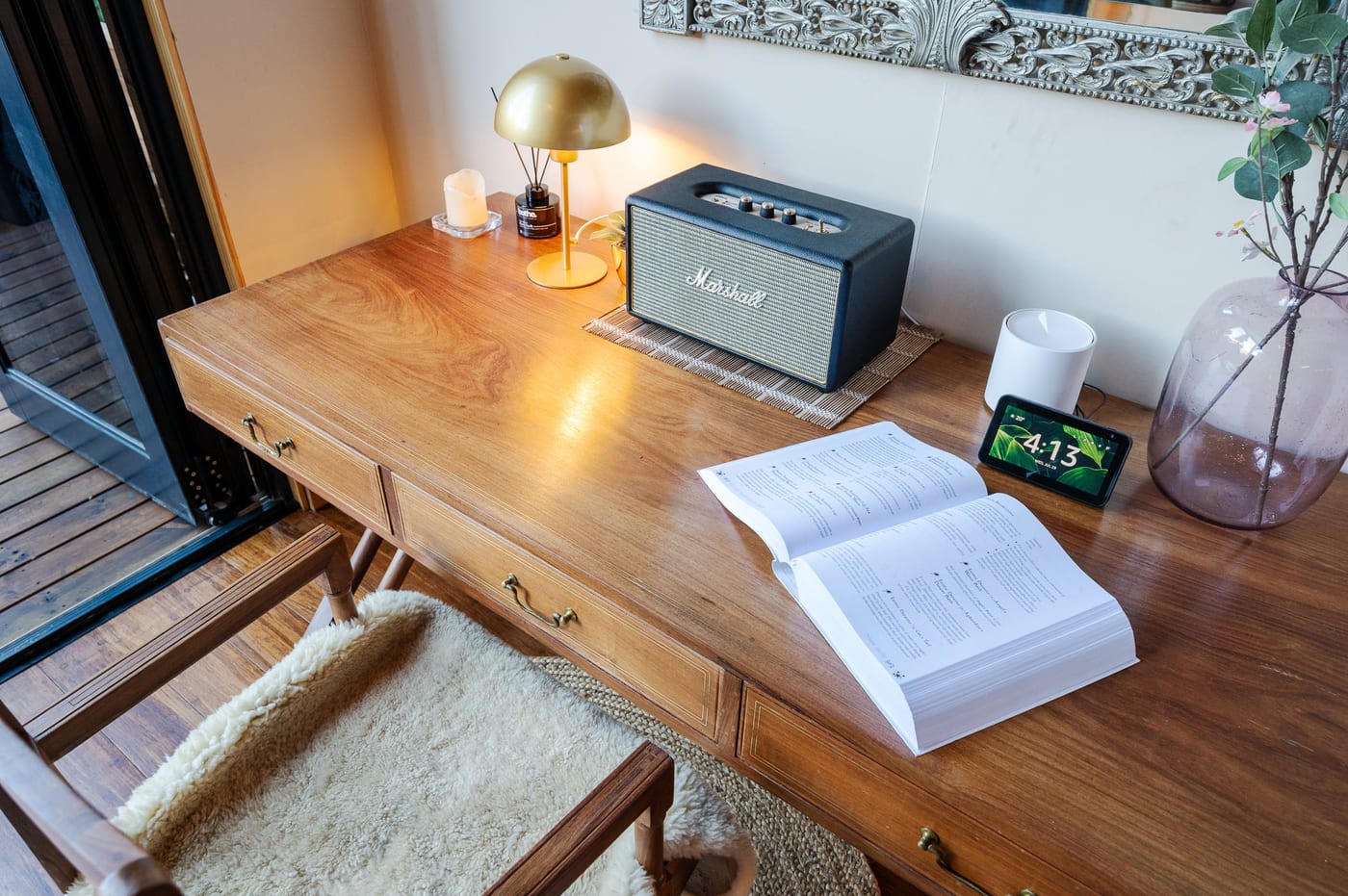 A Marshall speaker, brass lamp and an open book on the writing desk