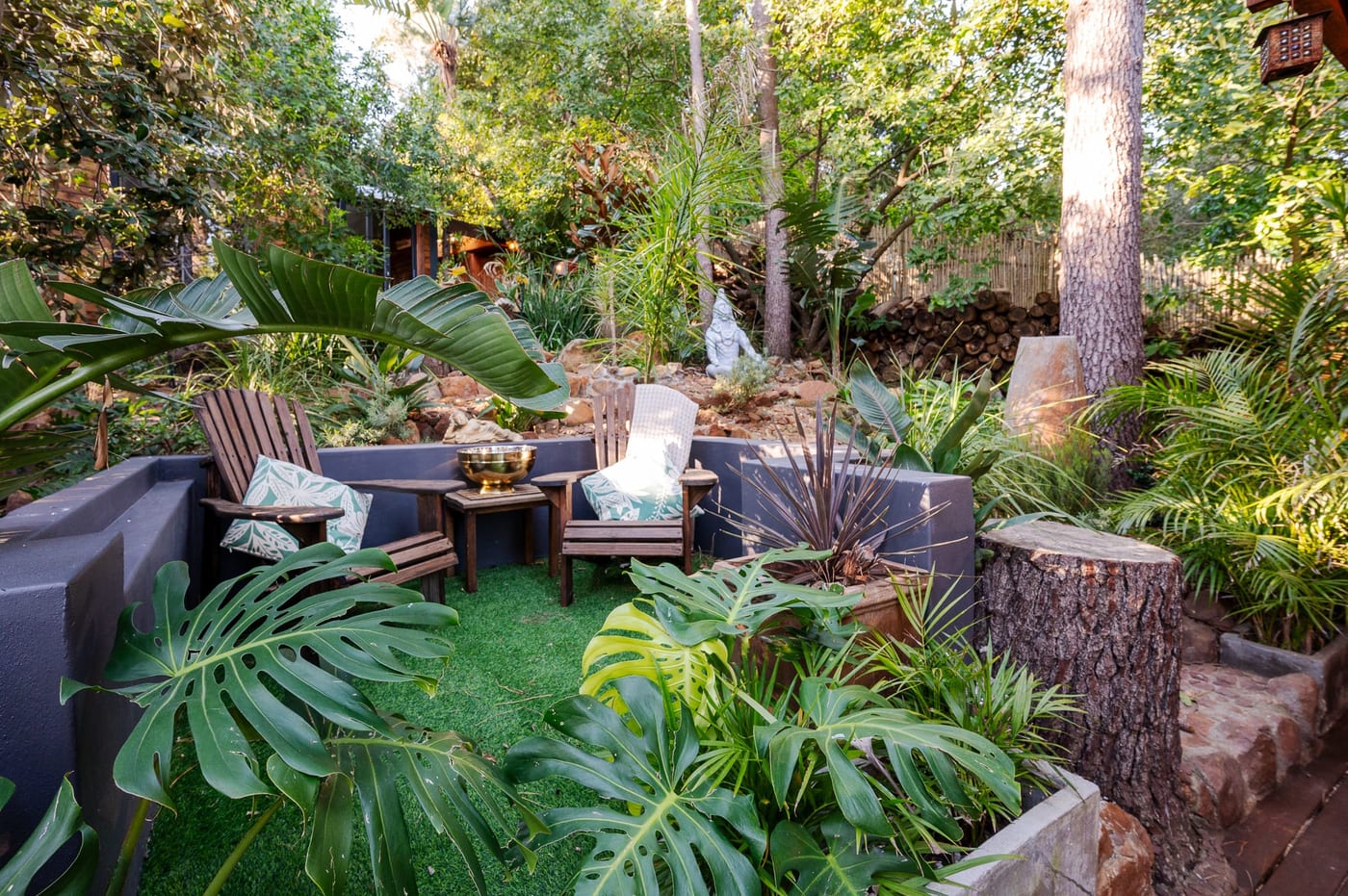 The garden seating nook among monstera and palms, with statues in the rockery