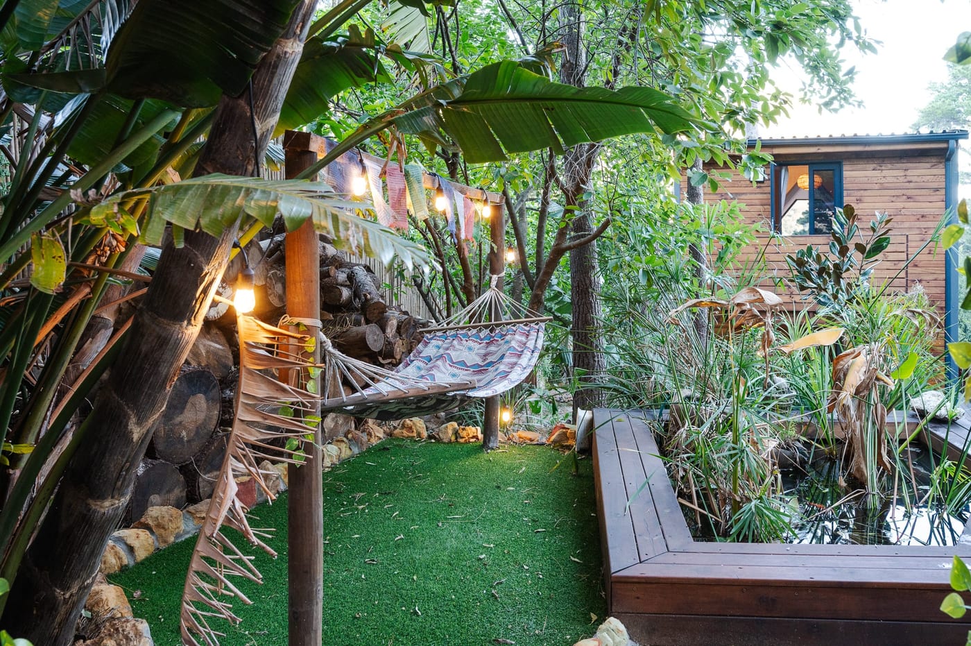 The hammock nook among banana palms, with the koi pond and cabin beyond
