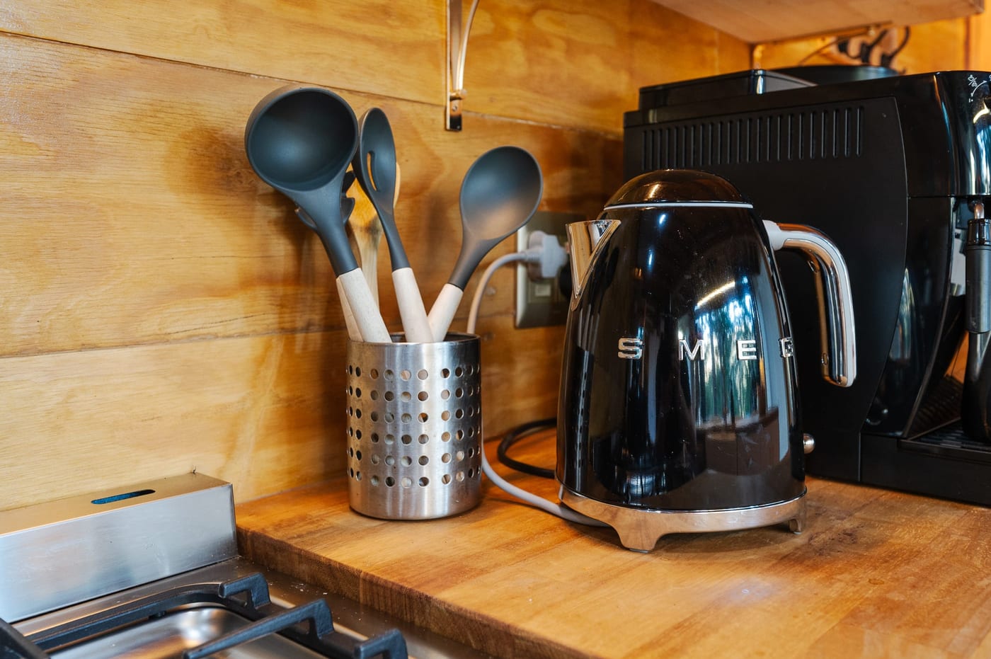 A black kettle and utensil pot on the butcher-block counter