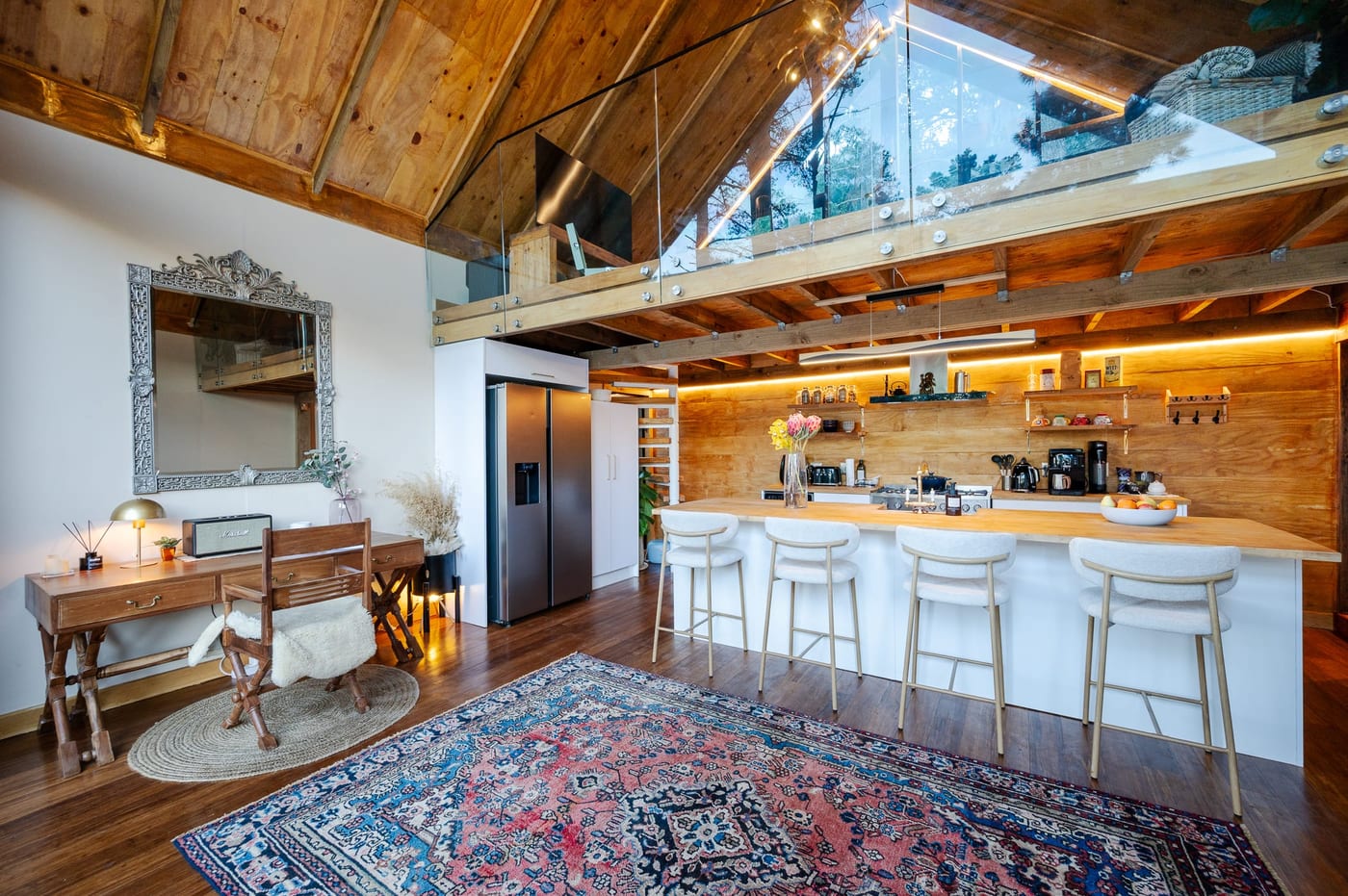 The open-plan living under the glass-railed mezzanine, desk on the far wall