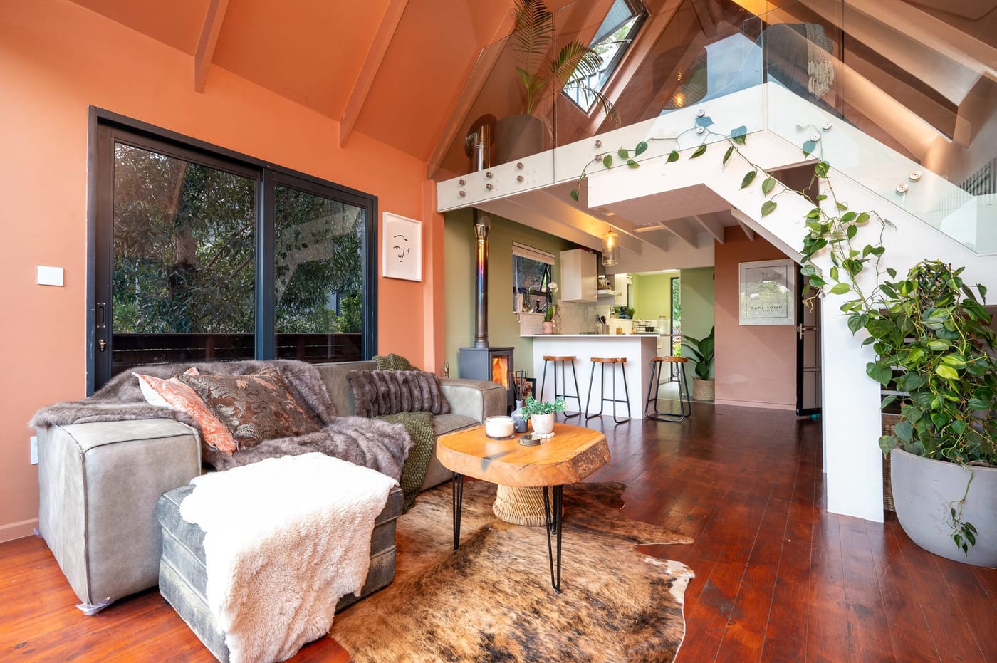 The leather sectional and live-edge table on a cowhide rug, stove lit alongside