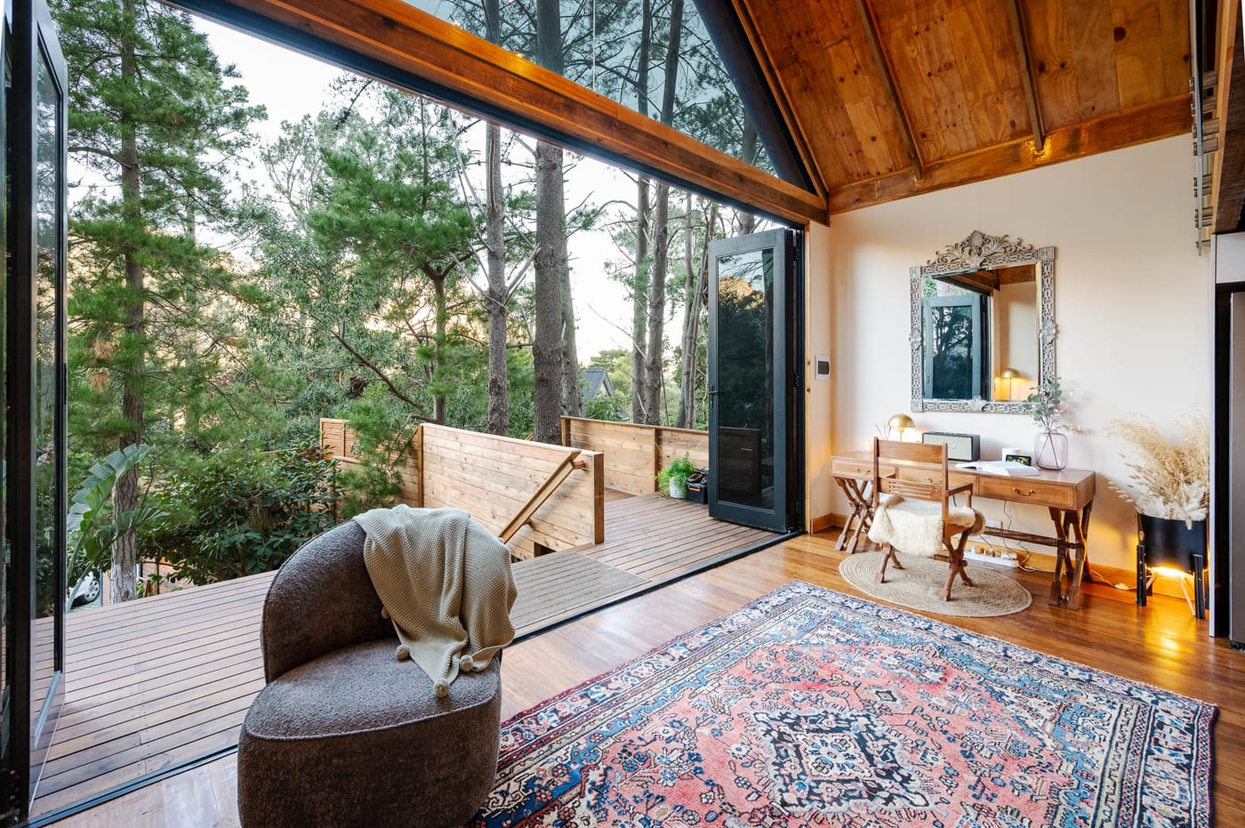 A swivel chair by the open doors, the writing desk and carved mirror beyond