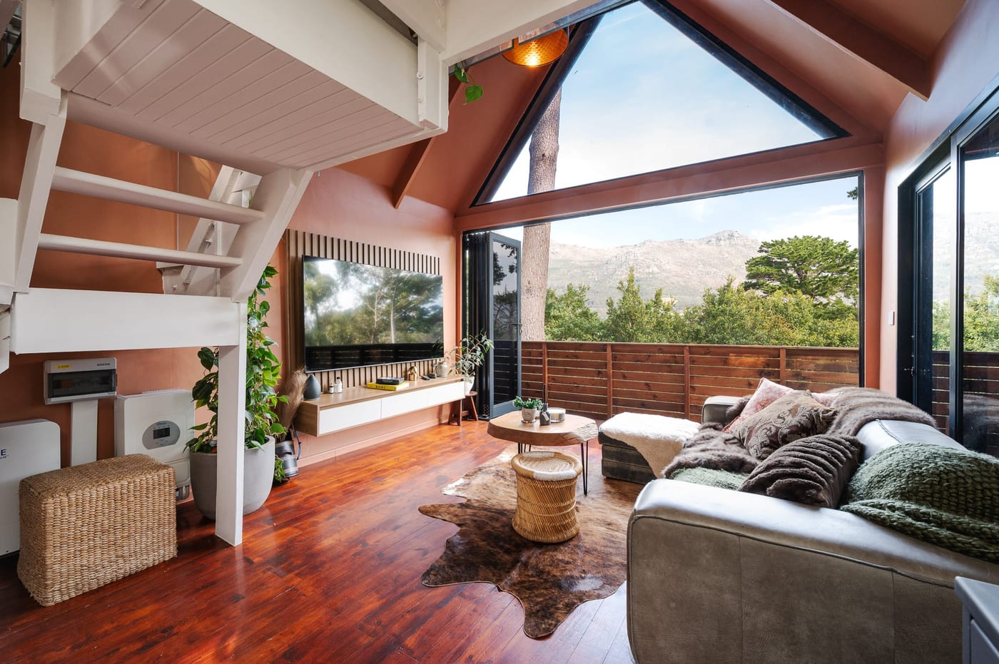 The television on its slatted timber panel, doors open to the deck and the ridge