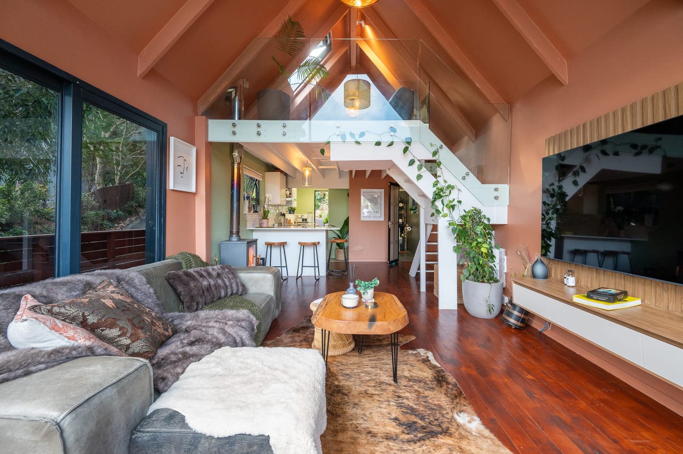 The full vaulted living room, mezzanine and white stair with the kitchen beyond
