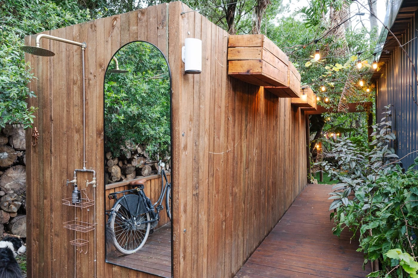 The outdoor rain shower on a timber wall beside an arched mirror