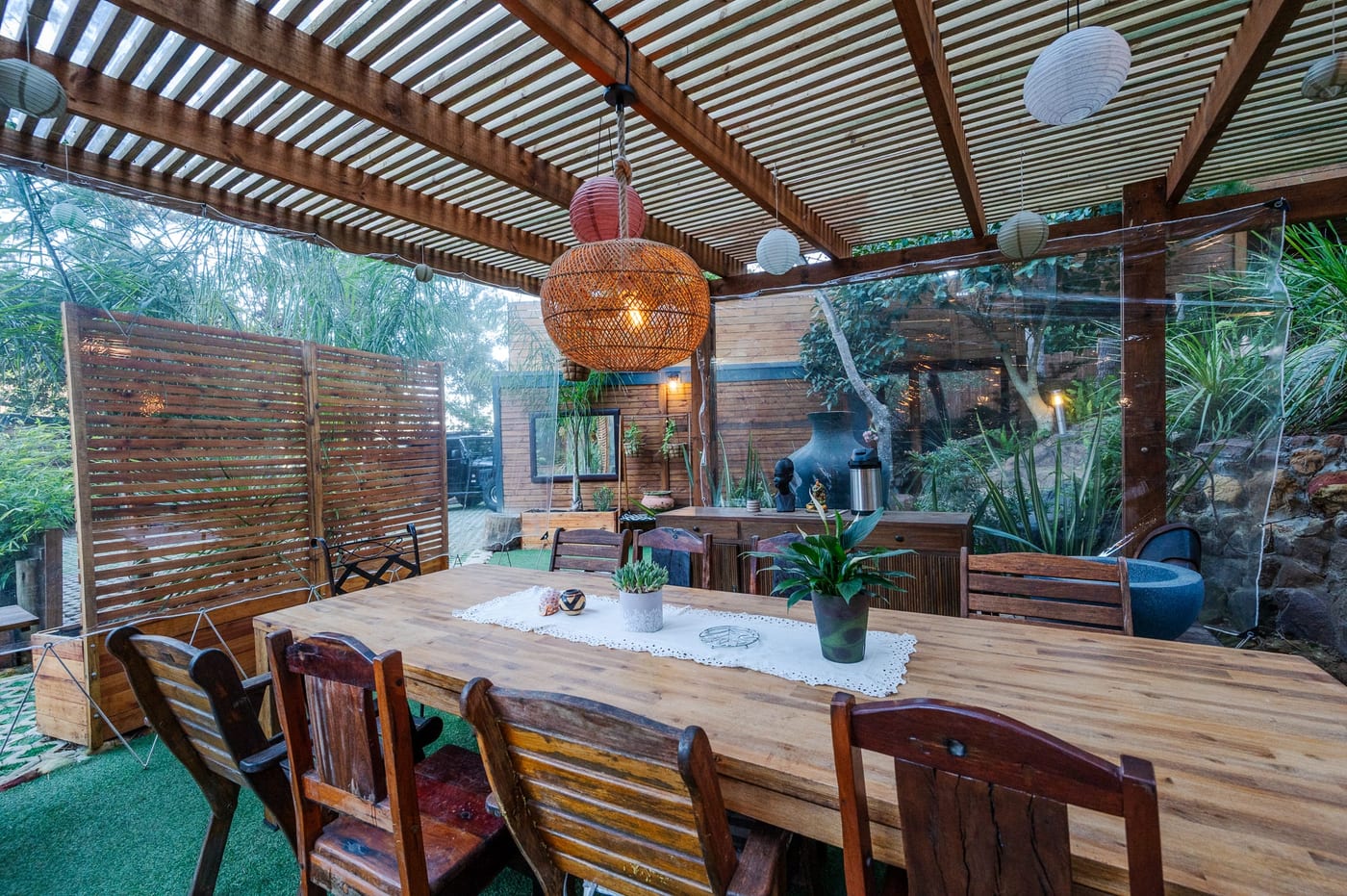 The long table under the pergola, rattan pendants and paper lanterns overhead