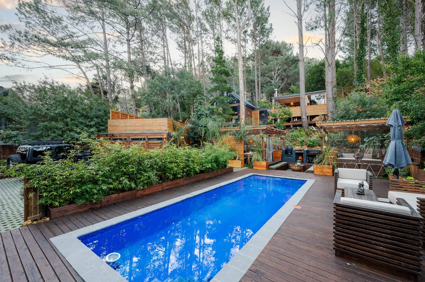 The pool at dusk, a pale sky above the pines and the terraces lit below