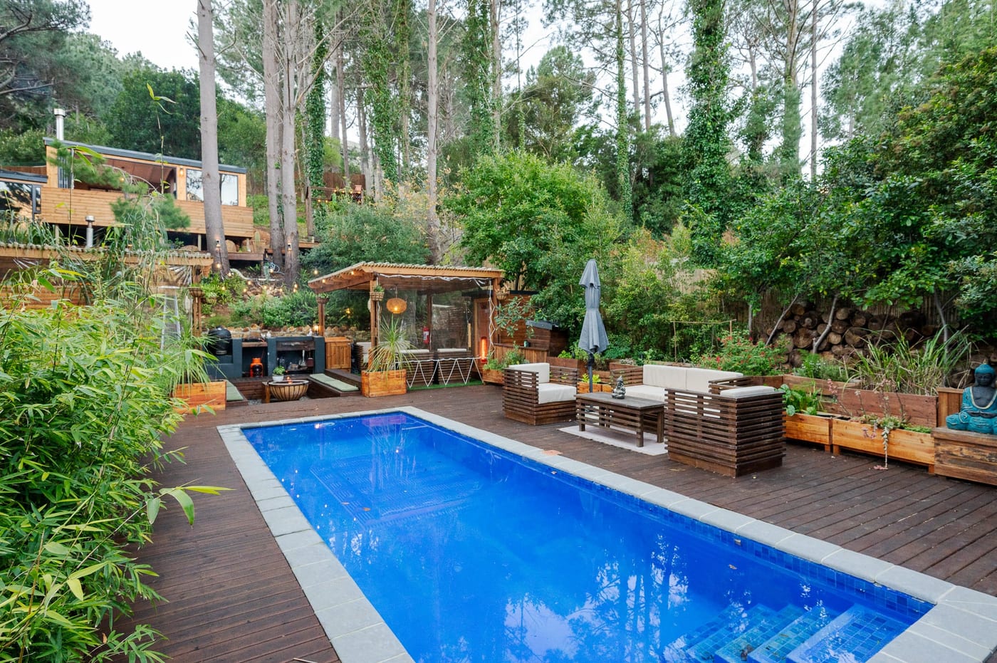 Deck loungers and a turquoise Buddha beside the pool, cabins rising behind