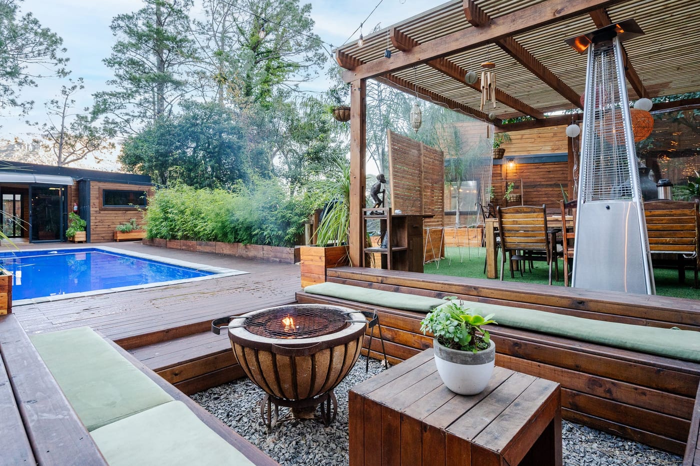 The pool at dusk beside the pergola, patio heater and dining set on the lawn
